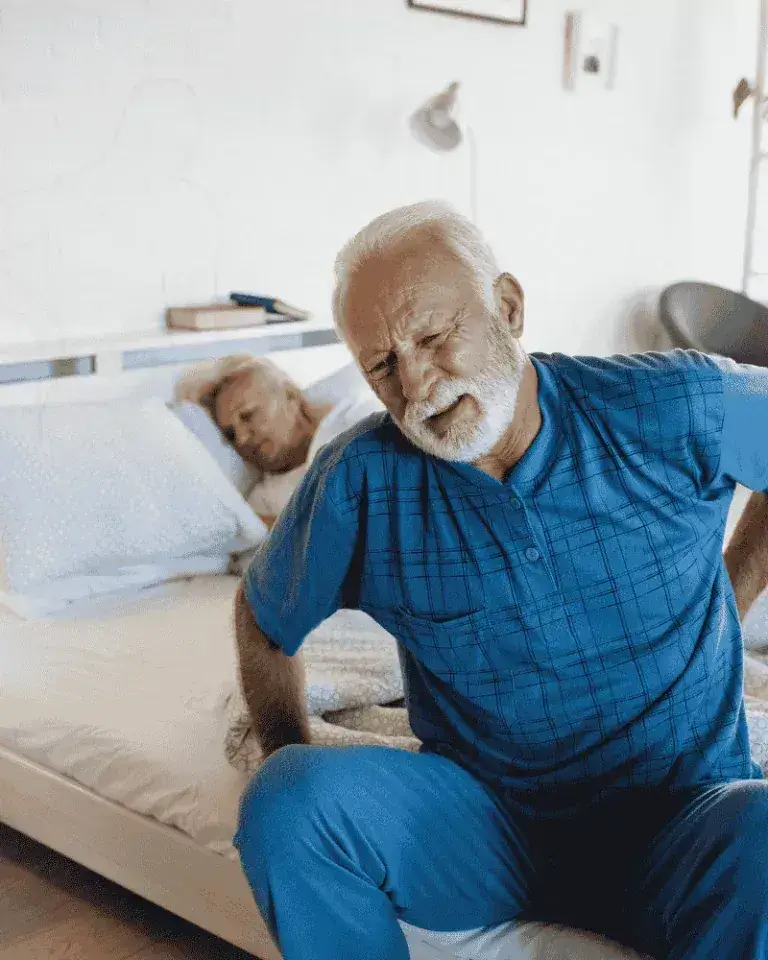 Senior man holding lower back in pain before starting Arialief supplement